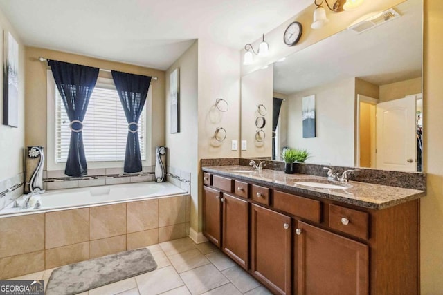 bathroom featuring tile patterned flooring, vanity, and tiled tub