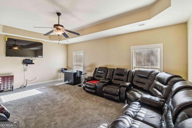 cinema room featuring a tray ceiling, ceiling fan, and carpet