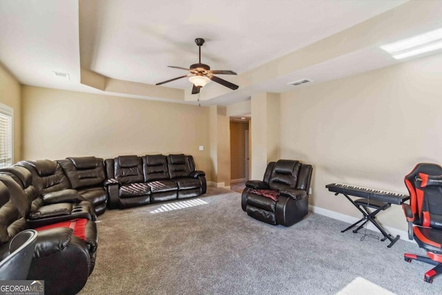 living room featuring carpet flooring, ceiling fan, and a tray ceiling