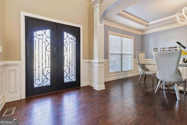 foyer entrance with ornate columns, dark hardwood / wood-style floors, a raised ceiling, crown molding, and french doors