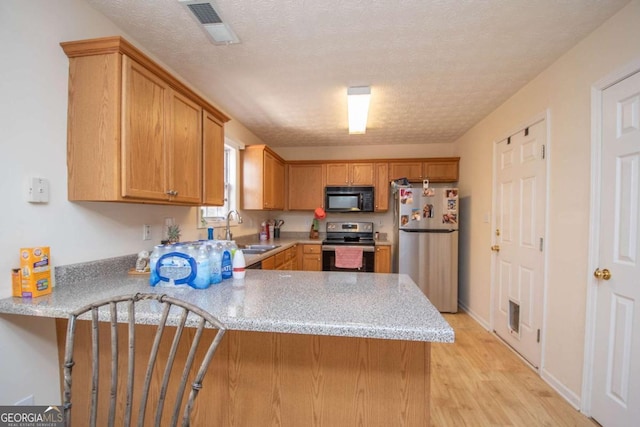 kitchen featuring sink, stainless steel appliances, kitchen peninsula, light hardwood / wood-style floors, and a textured ceiling