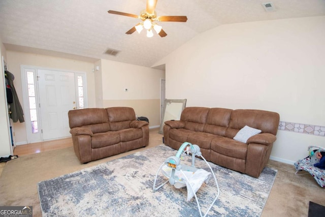 living room with a textured ceiling, light colored carpet, vaulted ceiling, and ceiling fan