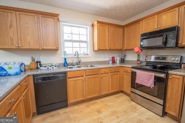 kitchen with a textured ceiling, sink, light hardwood / wood-style floors, and black appliances