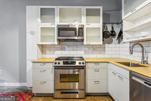 kitchen with tasteful backsplash, white cabinetry, sink, and stainless steel appliances