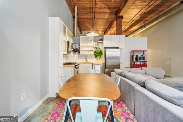 dining area with wooden ceiling, sink, beamed ceiling, and concrete floors