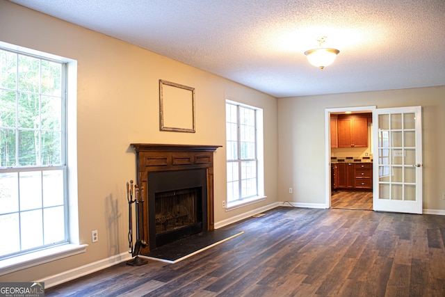 unfurnished living room featuring a textured ceiling, dark hardwood / wood-style floors, and a wealth of natural light