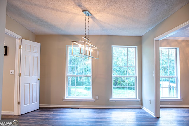 unfurnished dining area featuring dark hardwood / wood-style floors, a healthy amount of sunlight, and a chandelier