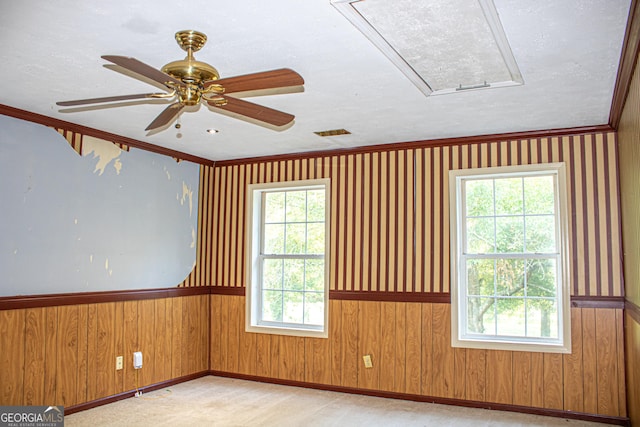 carpeted empty room with a healthy amount of sunlight, ceiling fan, and ornamental molding