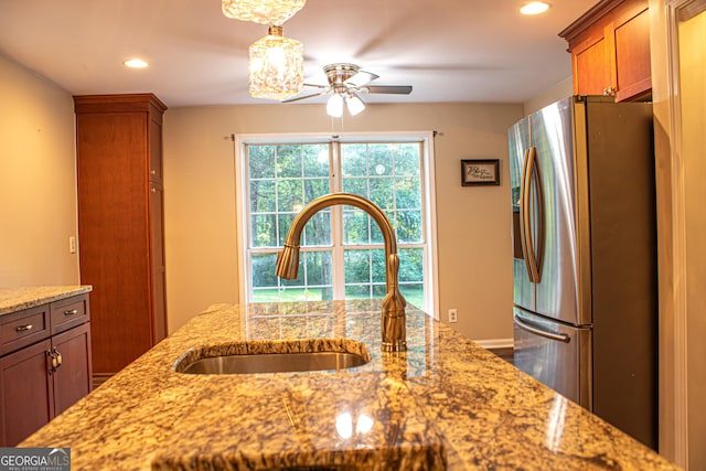 kitchen featuring stainless steel fridge with ice dispenser, light stone counters, ceiling fan, and sink