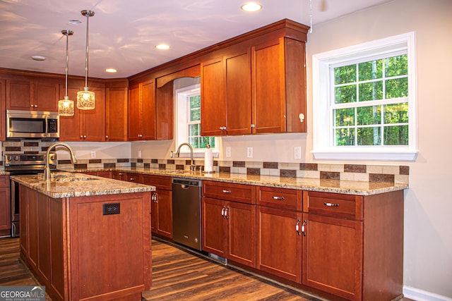 kitchen featuring pendant lighting, a kitchen island with sink, sink, dark hardwood / wood-style floors, and appliances with stainless steel finishes