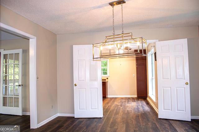 unfurnished dining area with a textured ceiling and dark hardwood / wood-style floors