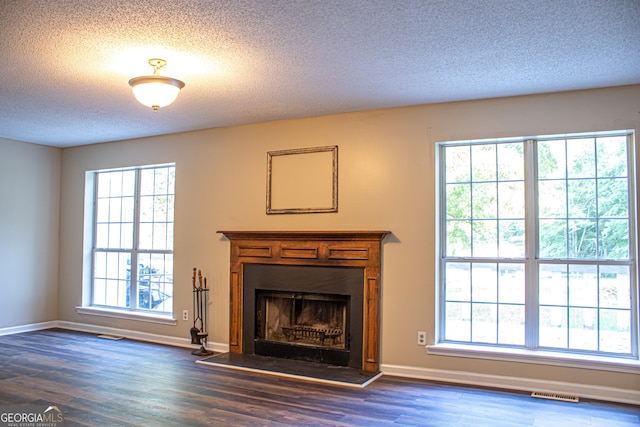 unfurnished living room with dark hardwood / wood-style flooring and a textured ceiling