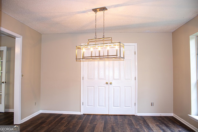 unfurnished dining area with a textured ceiling and dark wood-type flooring