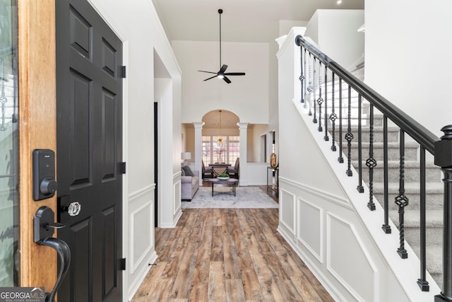 foyer featuring decorative columns, ceiling fan, and wood-type flooring