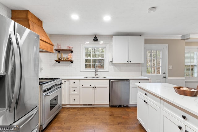 kitchen with white cabinetry, sink, stainless steel appliances, backsplash, and wood-type flooring