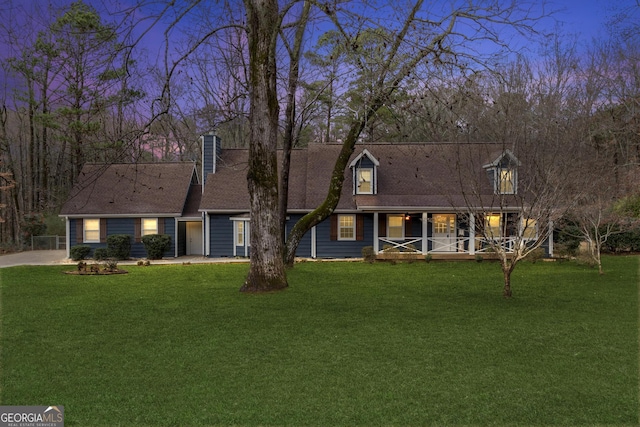 cape cod house featuring a yard and a porch