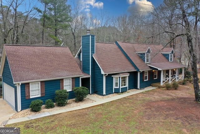 new england style home featuring a porch, a garage, and a front yard