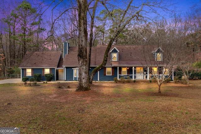 new england style home with covered porch and a lawn