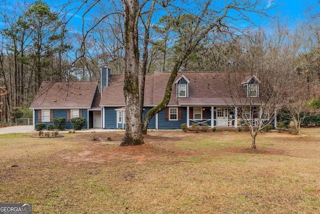 new england style home featuring a porch and a front lawn