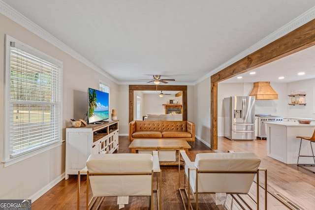 living room featuring crown molding, light hardwood / wood-style flooring, and ceiling fan