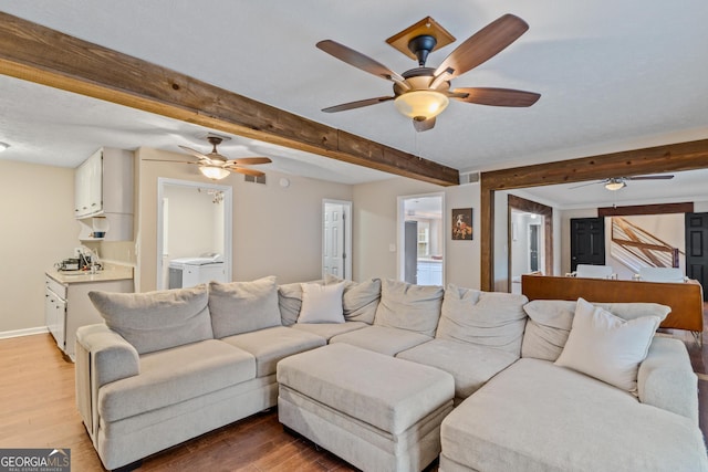 living room with hardwood / wood-style floors, beam ceiling, and washing machine and dryer