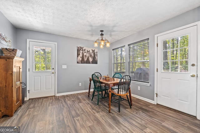 dining space featuring a textured ceiling, an inviting chandelier, and dark wood-type flooring