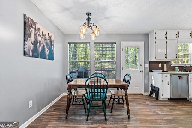 dining area featuring dark hardwood / wood-style floors, a healthy amount of sunlight, a textured ceiling, and a chandelier