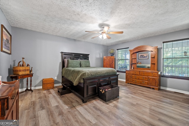 bedroom with a textured ceiling, light hardwood / wood-style floors, and ceiling fan