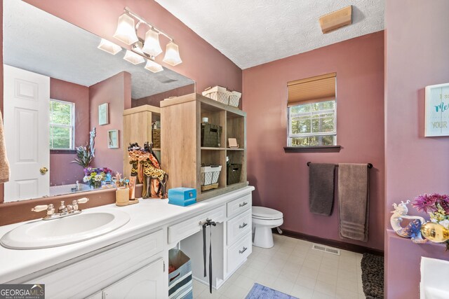 bathroom with vanity, a textured ceiling, toilet, and plenty of natural light