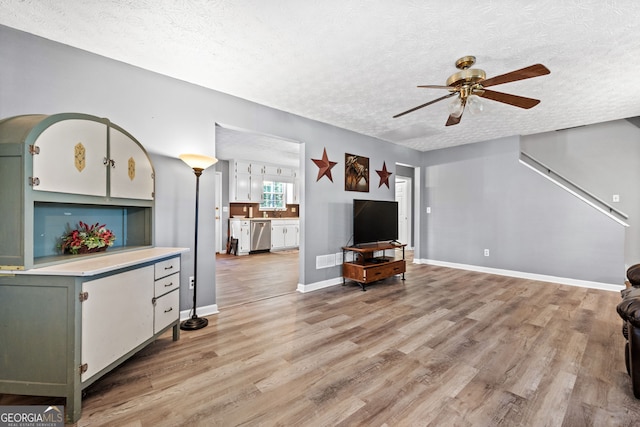 living room featuring a textured ceiling, light hardwood / wood-style floors, and ceiling fan