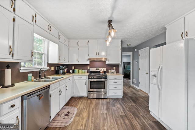 kitchen with sink, dark hardwood / wood-style floors, decorative light fixtures, white cabinetry, and stainless steel appliances