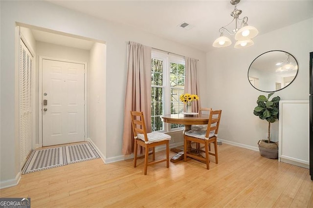 dining area featuring light wood-type flooring and an inviting chandelier