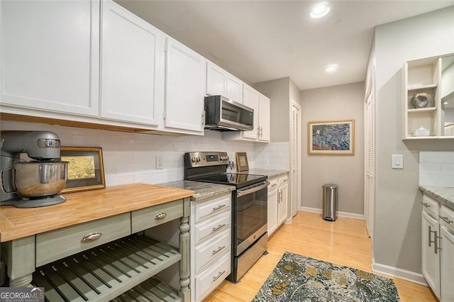 kitchen with white cabinetry, light hardwood / wood-style floors, stainless steel appliances, decorative backsplash, and light stone countertops