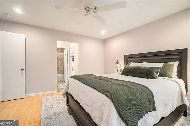 bedroom featuring ceiling fan, ensuite bath, and light hardwood / wood-style floors