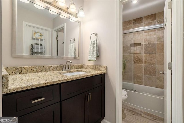 full bathroom with toilet, enclosed tub / shower combo, hardwood / wood-style floors, and vanity