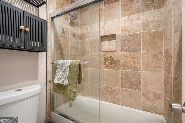 bathroom with shower / bath combination with glass door and toilet