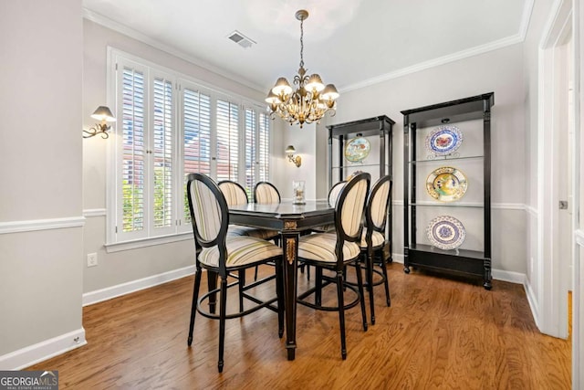 dining space with hardwood / wood-style floors, crown molding, a wealth of natural light, and a chandelier