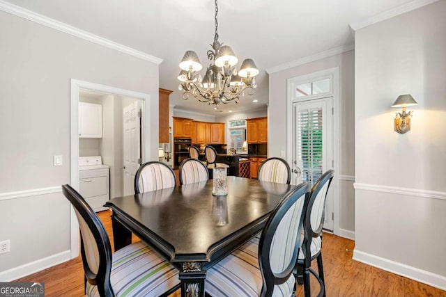 dining space featuring light wood-type flooring, an inviting chandelier, crown molding, and washer / clothes dryer