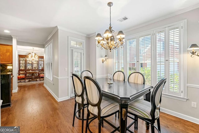 dining space with an inviting chandelier, crown molding, and light hardwood / wood-style floors