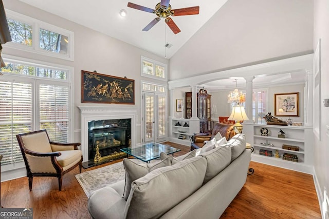 living room featuring hardwood / wood-style flooring, decorative columns, ceiling fan, a fireplace, and high vaulted ceiling