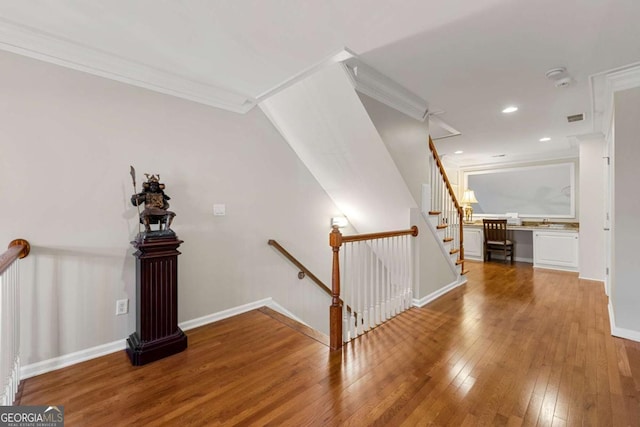 stairs featuring built in desk, wood-type flooring, and ornamental molding