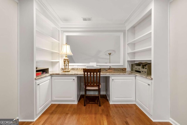 unfurnished office with built in desk, built in shelves, light wood-type flooring, and crown molding