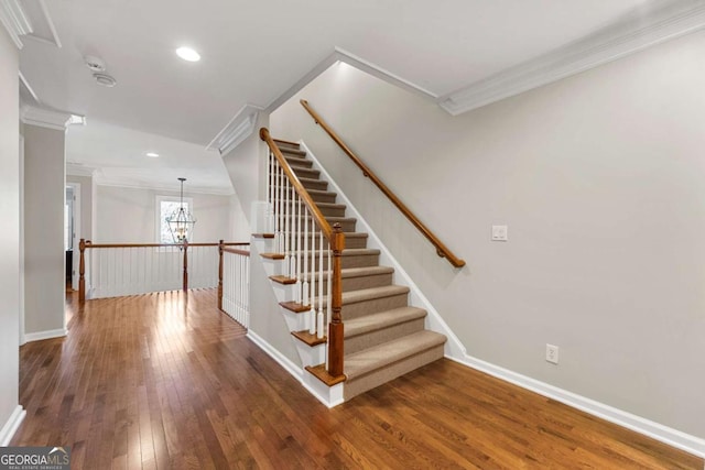 staircase featuring a chandelier, ornamental molding, and hardwood / wood-style flooring