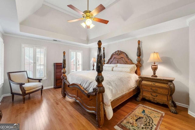 bedroom featuring hardwood / wood-style flooring, ceiling fan, ornamental molding, and a raised ceiling