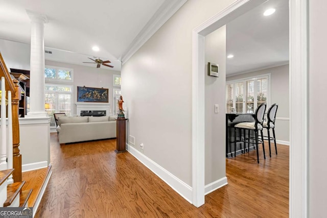 hall with decorative columns, hardwood / wood-style flooring, and crown molding