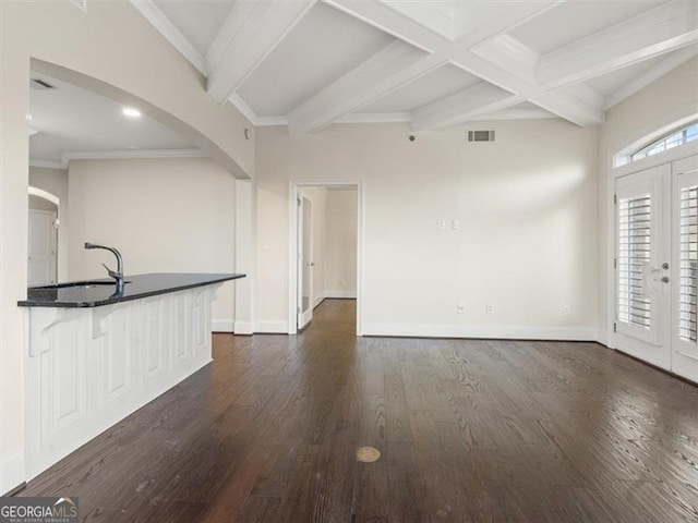 unfurnished living room featuring sink, coffered ceiling, dark wood-type flooring, beam ceiling, and french doors