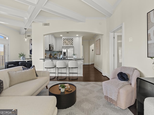 living room with beamed ceiling, coffered ceiling, sink, and hardwood / wood-style floors