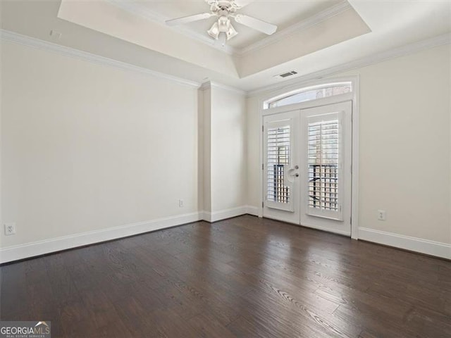 spare room with dark hardwood / wood-style flooring, a tray ceiling, crown molding, and ceiling fan