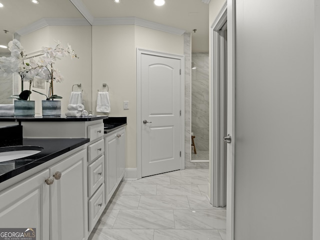 bathroom with a tile shower, vanity, and ornamental molding