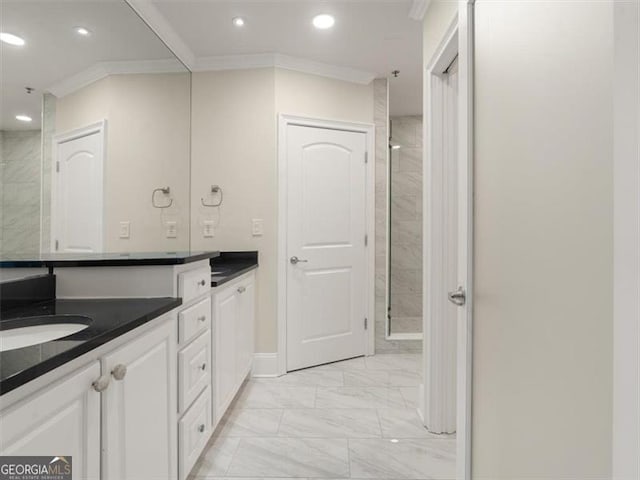 bathroom with ornamental molding, a tile shower, and vanity